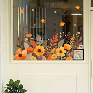 Detail of autumn floral window clings featuring orange flowers and fallen maple leaves