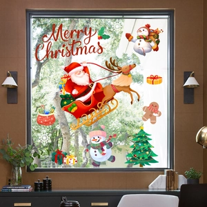 Close-up of festive Christmas window decals featuring Santa, snowman, and reindeer sled