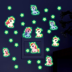 Macro detail of glowing unicorn and star wall stickers around a light switch in the dark