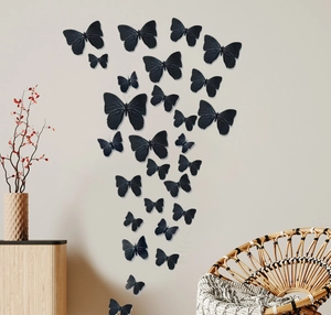 Detailed view of 3D black butterfly wall stickers on a grey textured wall in a modern living room