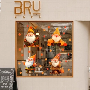 Detailed view of autumn gnome window clings and maple leaf decals on cafe glass