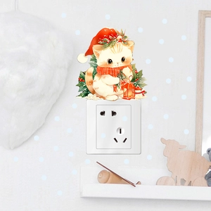 Detail of Christmas cat wall sticker with Santa hat and gift applied above a light switch