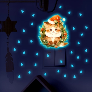 Close-up of luminous Christmas cat wall stickers glowing in ice blue light in dark room