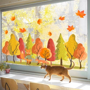 Close-up of autumn forest window decals with foxes and maple leaves on bright glass