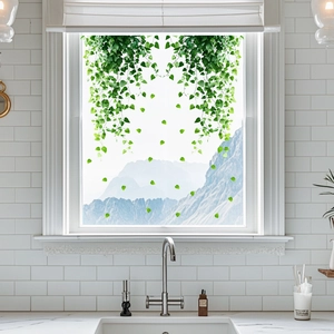 Detailed view of hanging green vine window stickers on a clear glass kitchen window