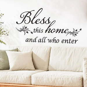 Detail of Bless This Home vinyl wall decal above a cozy sofa in a modern living room