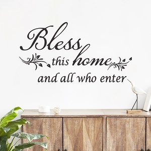 Detail view of Bless This Home vinyl wall decal above a wooden cabinet in a living room