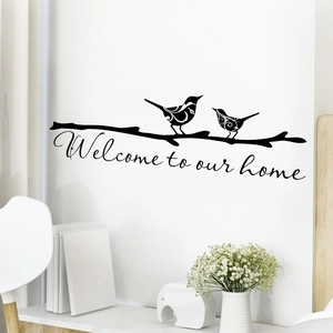 Dettaglio dell'adesivo murale Welcome to Our Home con uccelli e rami su parete bianca