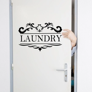 Close-up of black LAUNDRY door sticker with elegant scroll pattern on white surface