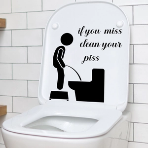 Détail d'un autocollant de toilette avec figurine et texte humoristique sur l'abattant blanc