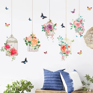 Detailed view of floral birdcage and butterfly wall decals on a clean white home wall