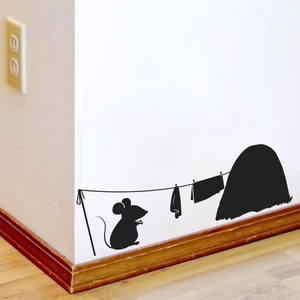 Detailed view of a black silhouette mouse hole wall sticker on a white baseboard