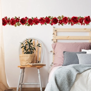 Detail of red rose wall decal sticker applied on a bedroom wall with vivid green leaves