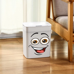 Close-up of white plastic trash bin with funny cartoon face sticker on wooden floor