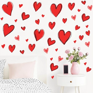 Detail showing hand-drawn red heart wall stickers arranged on a white bedroom wall