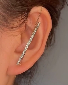 Detail of minimalist gold ear crawler with sparkling crystals worn on the earlobe
