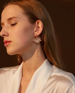 Detail of elegant white floral tassel earrings with long gold chains and crystal drops