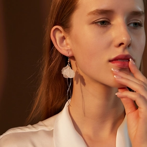 Macro detail of elegant hanging earrings with frosted white petals and spiral silver chains