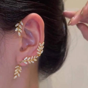 Macro shot of gold leaf crawler earrings with micro-set rhinestones on a female ear
