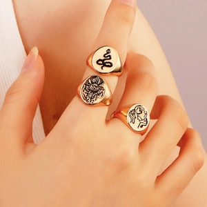 Close-up of vintage gold letter rings with engraved snake and sun patterns on fingers