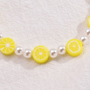 Pulsera artesanal de perlas blancas y dijes de rodajas de limón amarillas de arcilla