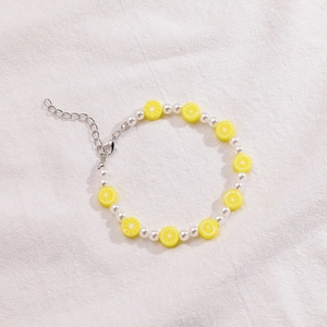 Primer plano detallado de pulsera hecha a mano con perlas blancas y dije de limón