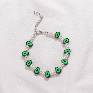 Detalle de pulsera de cuentas con perlas blancas, dije de aguacate y cierre de langosta