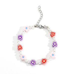 Pulsera artesanal con perlas blancas y flores de arcilla coloridas sobre fondo blanco