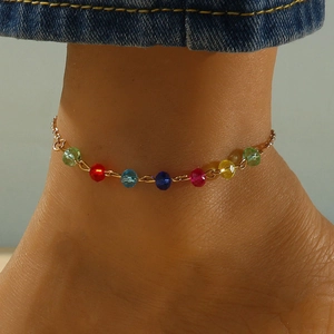 Bracelet de cheville en perles de cristal colorées et chaîne dorée porté sur la cheville