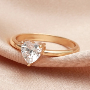 Elegant rose gold heart zircon ring with three-prong setting on pink silk background