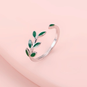 Detail of silver adjustable ring with green enamel olive leaf design on pink background