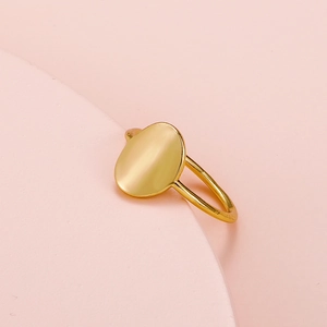 Close-up of minimalist gold geometric ring with polished finish on pink background