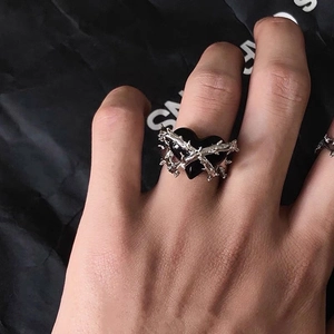 Close-up of gothic thorn heart ring with black stone on hand in punk style