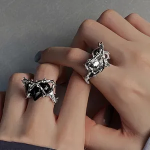 Detail of gothic silver thorn rings with black heart stone on textured background