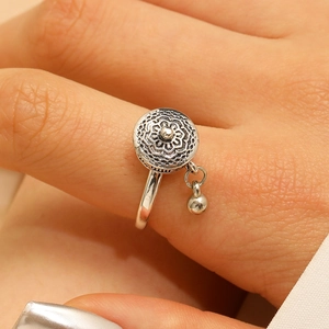 Macro shot of retro mandala flower engraved open ring with a small beaded pendant detail