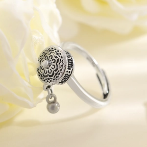 Detailed close-up of a vintage silver spinning ring with floral engraving and small charm