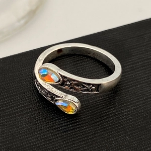 Macro shot of vintage silver bypass ring with colorful pear-cut gemstones and floral engraving