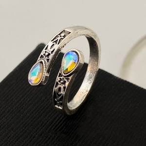 Detailed close-up of antique silver heart ring with iridescent teardrop stones