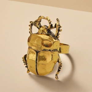 Detailed macro view of retro gold beetle ring with intricate insect texture and metallic finish