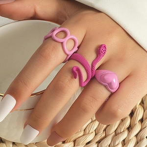 Detailed macro view of 3-piece pink heart and snake ring set on hand with tea cup