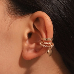 Detail view of irregular gold ear cuffs set with pearls, rhinestones and heart pendant