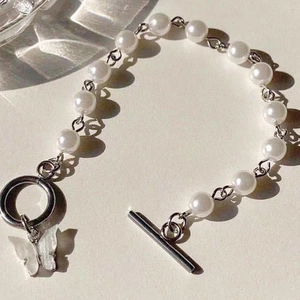 Elegant butterfly charm pearl bracelet featuring a minimalist silver-tone toggle clasp design