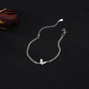 Detail of silver double-layer bead bracelet with sparkling butterfly pendant on black background