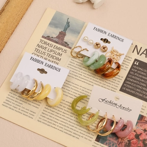 Dettaglio del set di orecchini vintage con perle e cerchi in resina su carta bianca