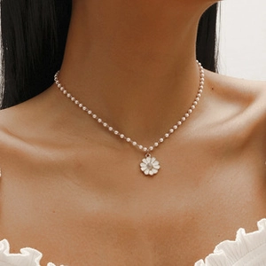 Detailed close-up of a pearl necklace featuring a delicate white daisy pendant charm