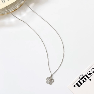 Detailed macro view of silver flower pendant with zircon stones and heart motif on a cross chain