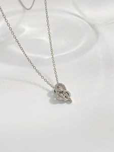 Macro shot of silver heart necklace with zircon inlay on wavy white background