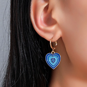 Detail showing blue enamel heart earrings with gold hoops on ear for size reference