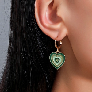 Close-up of green gradient heart earrings in gold finish worn by a model