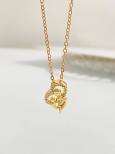 Macro shot of gold necklace with heart-shaped pendant depicting mother and child embrace